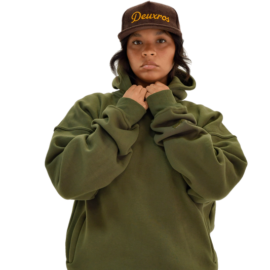 Color: Field Moss hoodie women's lifestyle shot, oversized relaxed fit with drop shoulders, styled with deuXros corduroy hat