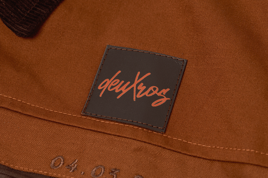 deuXros jacket close-up of leather patch label and date detail at chest pocket, brown cotton canvas