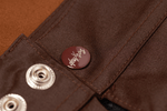Close-up of a brown fabric with a button and deuxros logo.